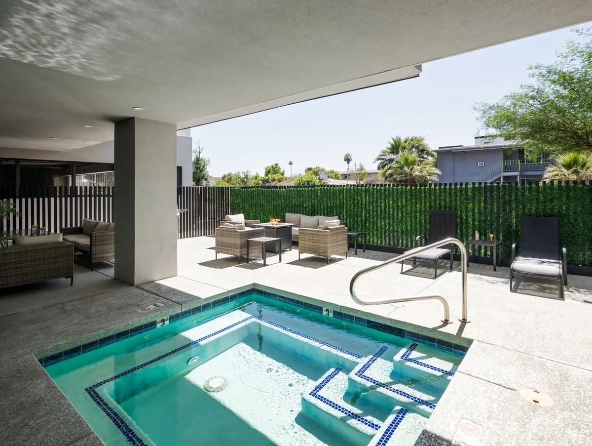 An outdoor hot tub area with a jacuzzi as the focal point, surrounded by lounge chairs and a stylish seating area. The space is tranquil, ideal for sunbathing, relaxing after a long day, or socializing with fellow guests, especially with sunset views enhancing the resort-style vibe.
