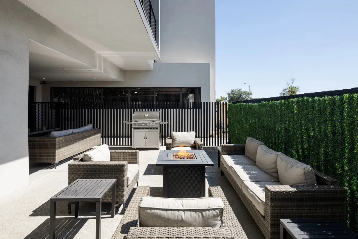 An inviting outdoor area featuring a modern grill, comfortable seating around a fire pit, and an overall setup ideal for group gatherings, casual barbecues, and evening relaxation. The space is designed for both dining and socializing, with a contemporary and cozy atmosphere.