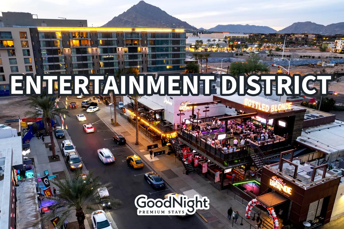 A dynamic exterior shot of the entertainment district, featuring prominent signage, a busy street lined with cars, bustling outdoor seating areas, and the mountains in the background. The lively scene suggests an area filled with nightlife, dining, and social events.